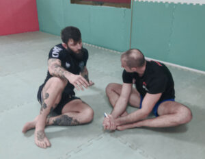 Maestro di Jiu Jitsu parla con allievo seduto su tatami
